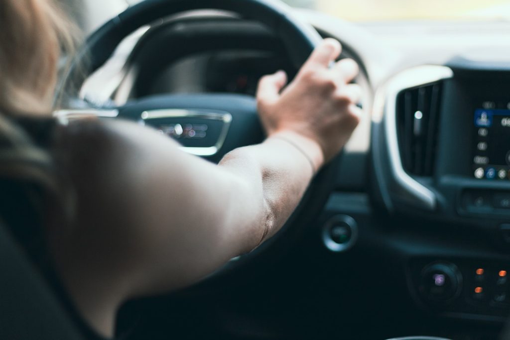 a woman driving a car with her hand on the steering wheel